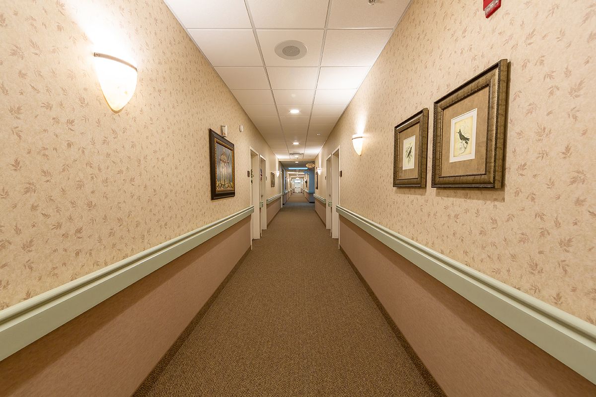 A long, carpeted hallway with framed artwork on the walls.