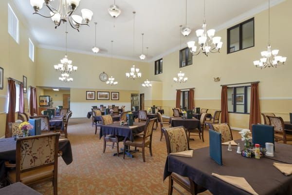 An elegant dining room with chandeliers and neatly arranged tables and chairs.