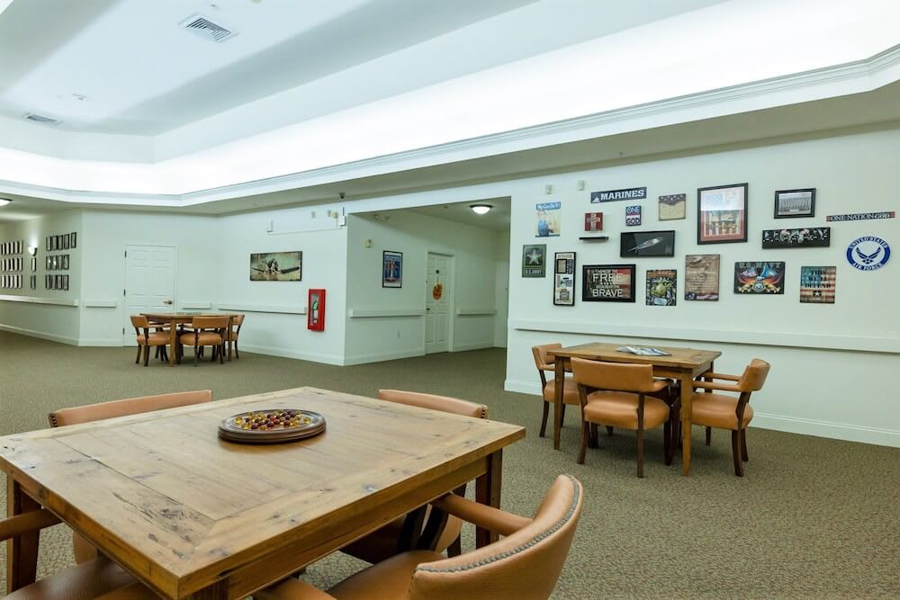 A dining area with wooden tables and chairs, adorned with wall art and illuminated by overhead lighting.