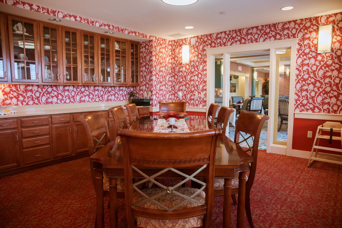 A cozy dining room with wooden furniture and vibrant red wallpaper.