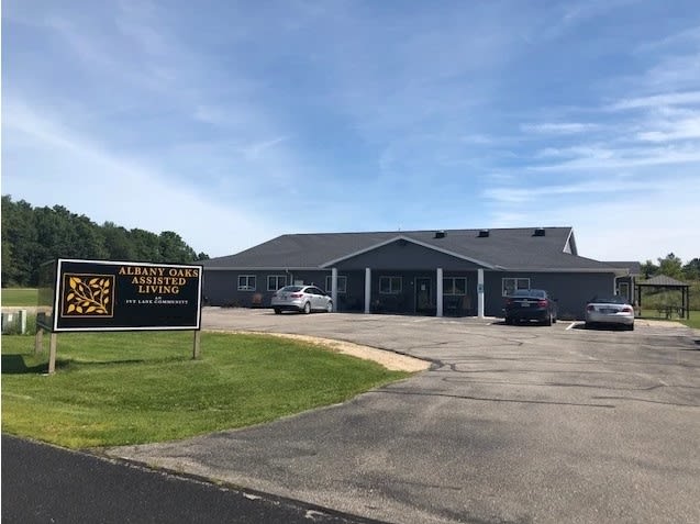 A church building with a parking lot and sign on a cloudy day.