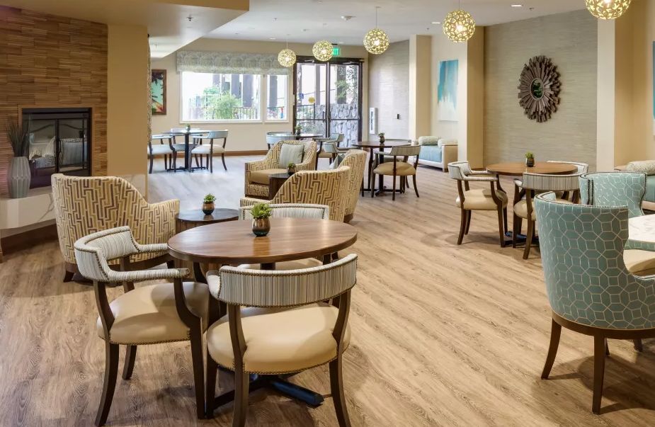 A modern and well-lit dining area with multiple tables and chairs, featuring wood flooring and contemporary decor.