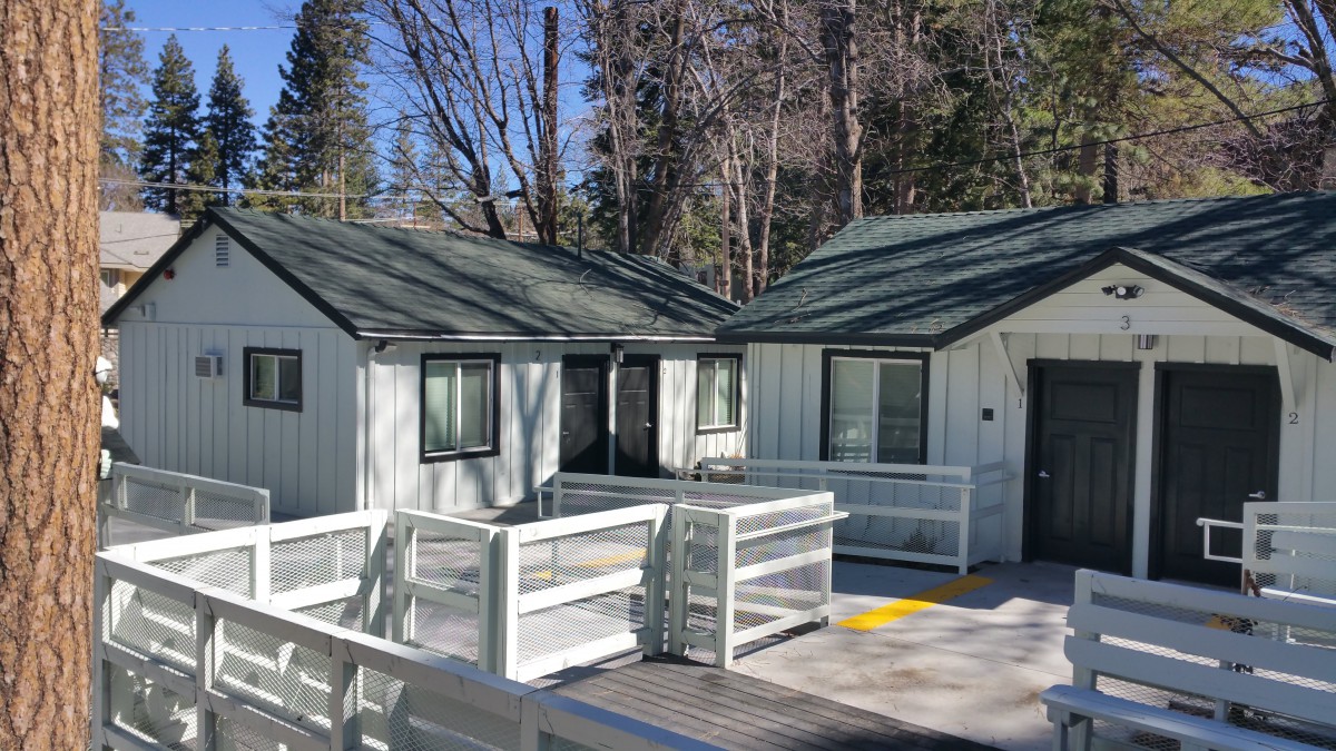 Small cabins nestled in a forest setting with wooden walkways.
