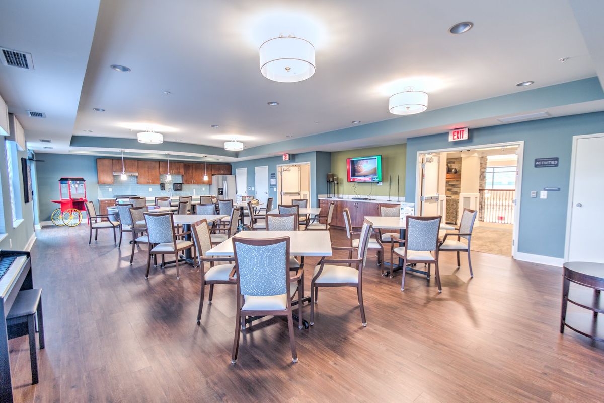 A spacious and well-lit dining area with several tables and chairs, featuring a modern interior design with wooden flooring.