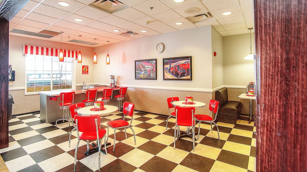 A retro-style diner interior with red chairs and a checkered floor.