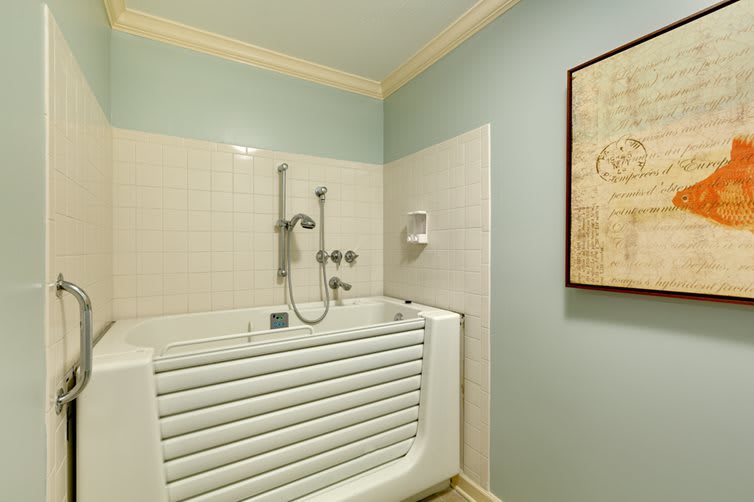 A modern bathroom featuring a compact bathtub with a sleek faucet and decorative wall art.