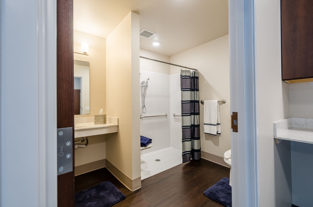 A modern bathroom with a walk-in shower, sink, and neatly arranged towels.
