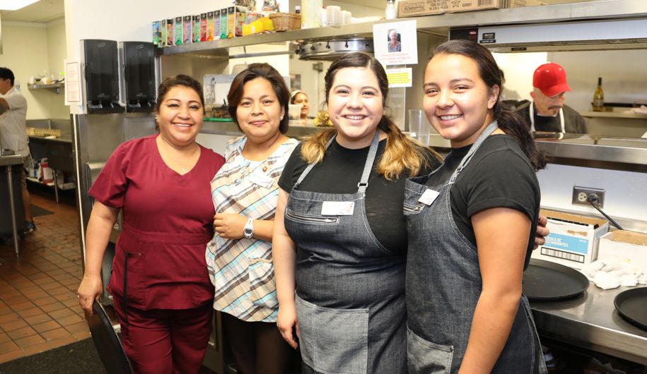 A group of women posing in a kitchen.