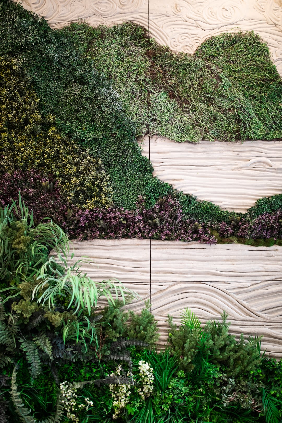 A modern green wall with lush plants and wooden panel accents.