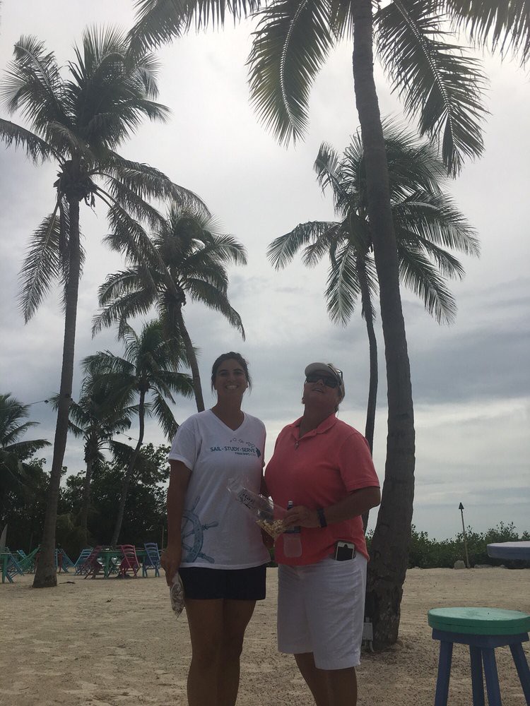 Two people standing on a beach with palm trees in the background.