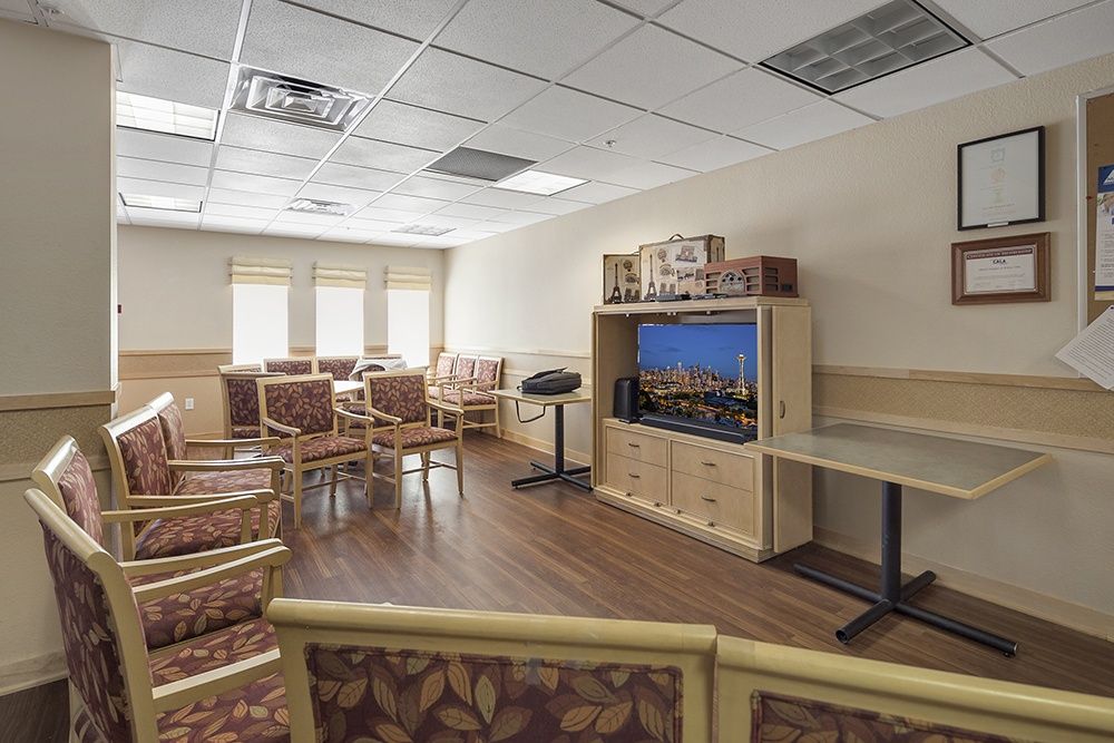 An empty waiting room with patterned chairs and a television.