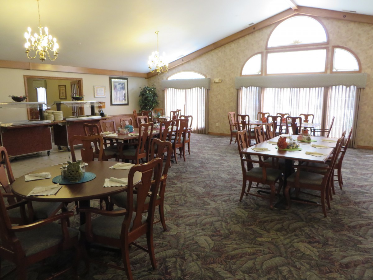 An elegant dining room with neatly arranged tables and chairs, illuminated by natural light from large windows.