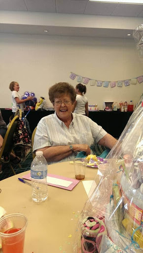 A cheerful older woman enjoying a gathering at a decorated table.