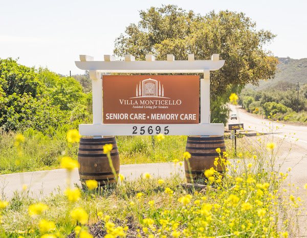 A scenic view of a winery sign surrounded by vibrant yellow flowers and lush greenery.