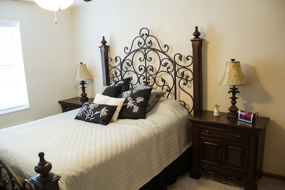 A stylish bedroom with an ornate wrought iron headboard and matching nightstands.