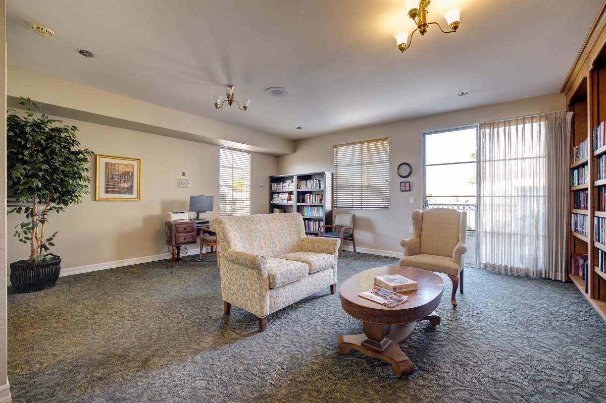 A cozy living room with a sofa, armchair, coffee table, and bookshelf.