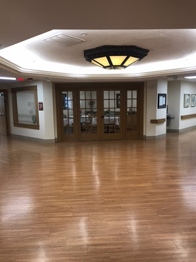 A view of a well-lit hallway featuring wooden flooring and elegant doors.