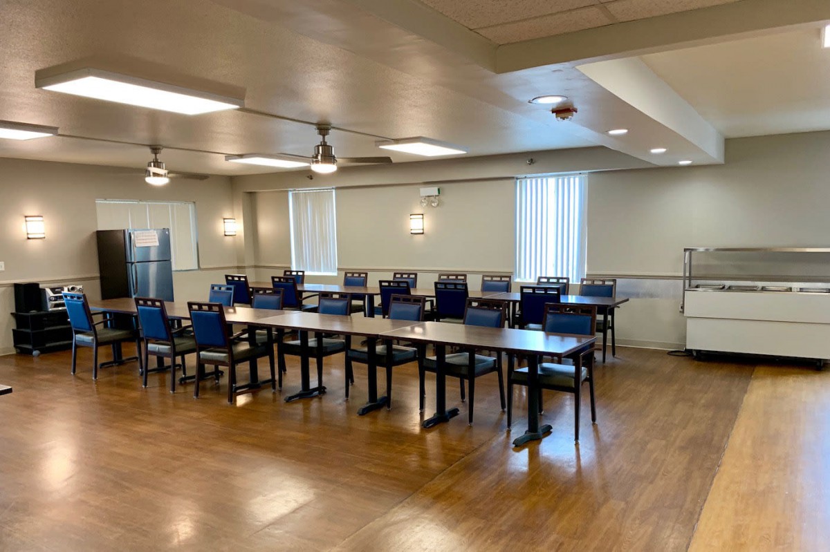 An empty dining room with neatly arranged tables and chairs under bright lighting.