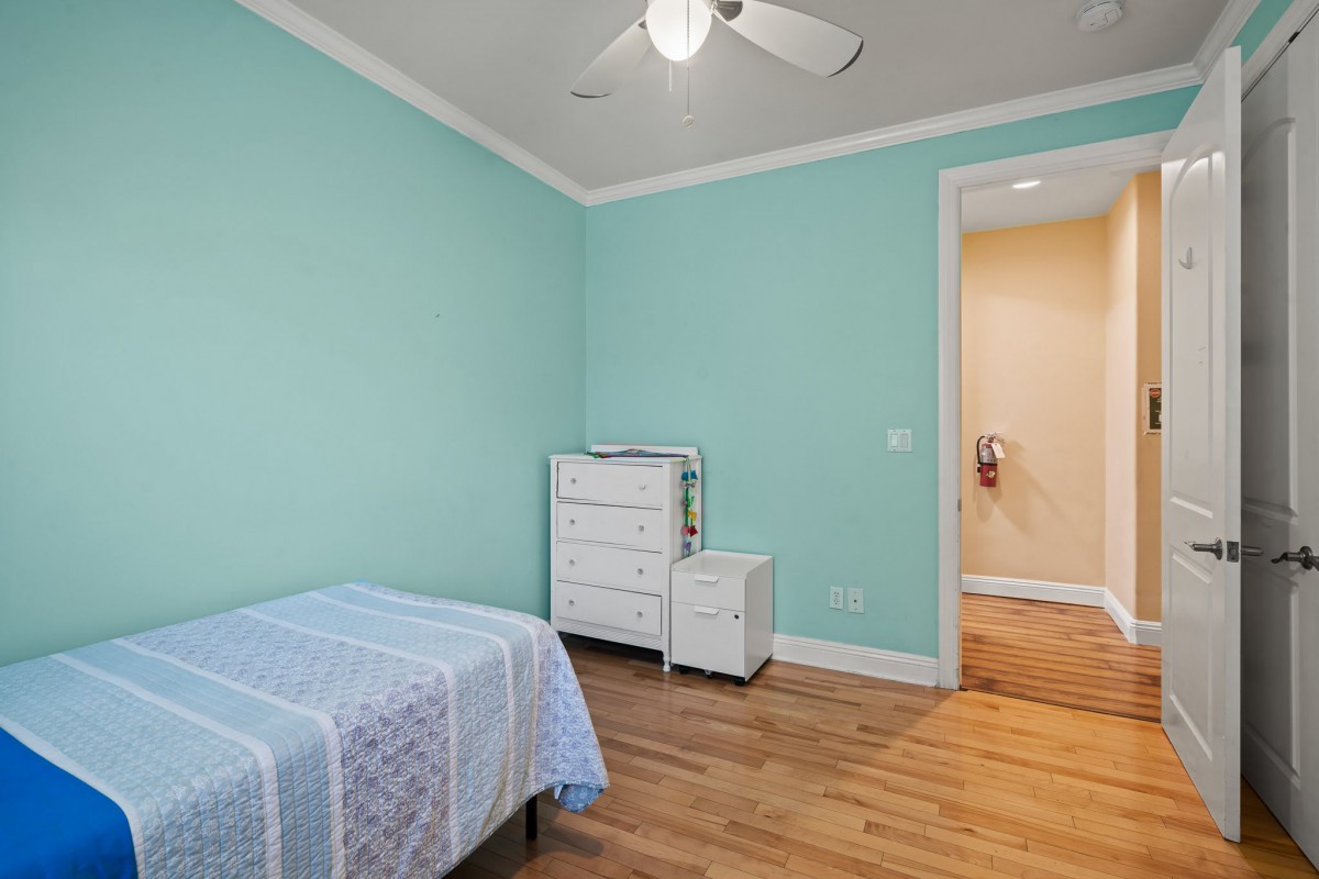A minimalist bedroom with light blue walls, featuring a single bed and wooden flooring.