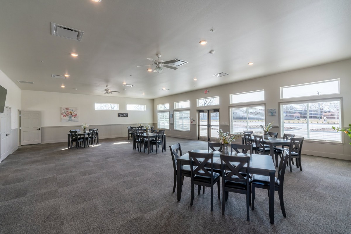 A spacious dining area with multiple tables and chairs, featuring large windows and modern lighting.