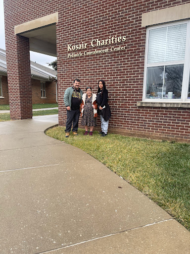 A family poses in front of a charity office, showcasing their support for community initiatives.