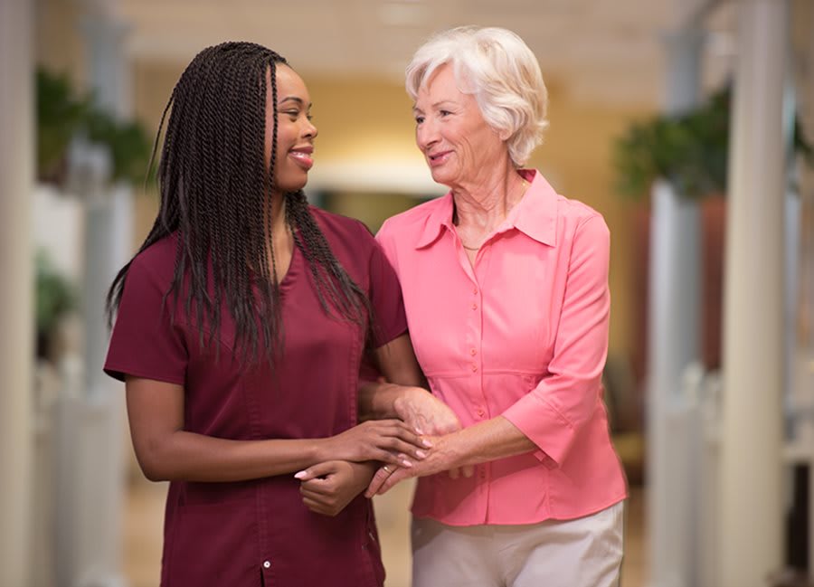 A caregiver assisting an elderly woman in a supportive environment.