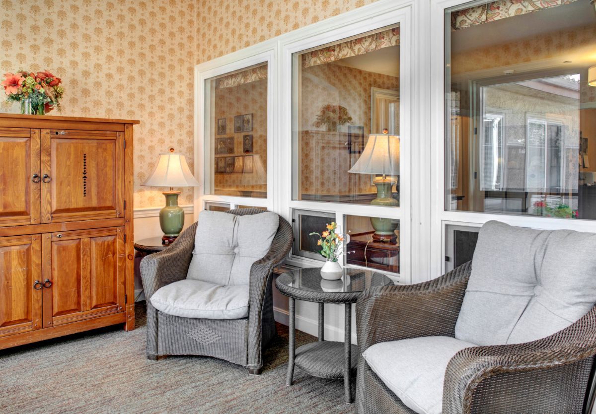 A cozy living room setup with comfortable chairs, a small table, and a lamp next to wooden furniture.
