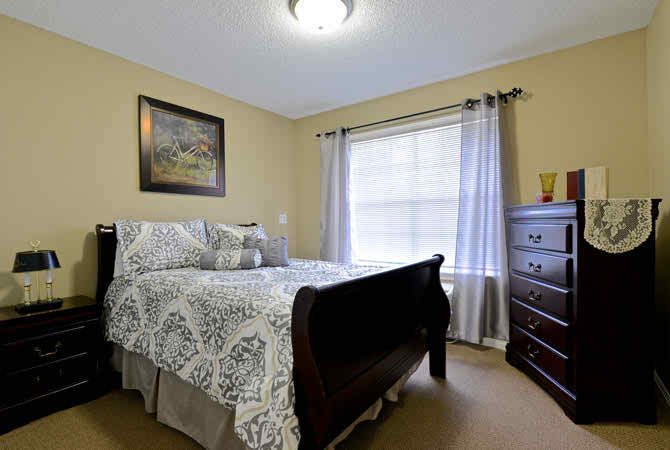 A cozy bedroom with a bed, dresser, and large window with curtains.