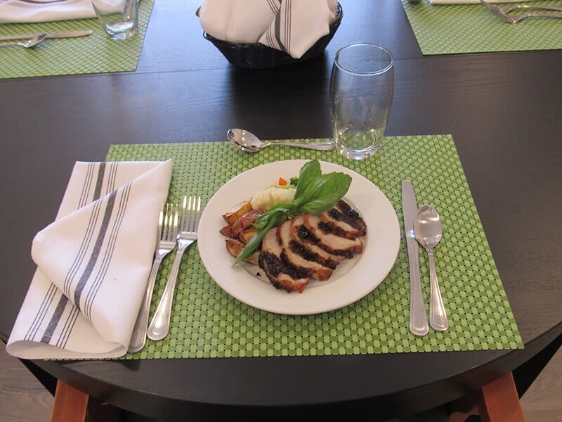 A neatly set dining table with a plated meal on a green placemat.