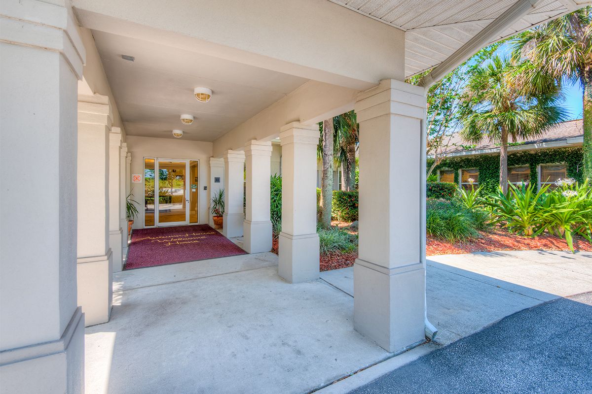 An inviting building entrance with columns and landscaped surroundings.