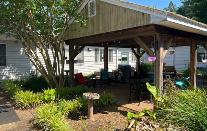 A cozy outdoor patio area with seating, surrounded by lush garden plants.