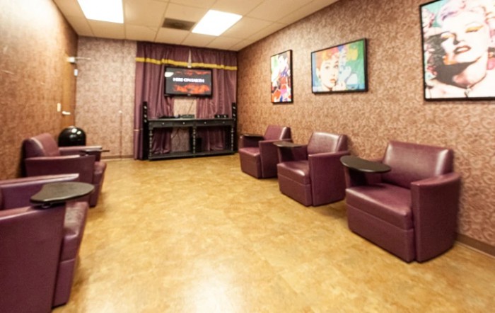 A cozy waiting room featuring comfortable seating, colorful artwork, and a television.