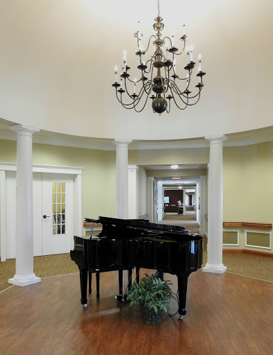 A beautifully designed lobby featuring a grand piano and an elegant chandelier, accentuated by classic columns.