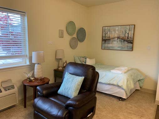 A cozy bedroom with a leather chair, soft bed, and decorative wall art.