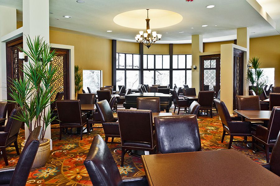 A well-appointed conference room featuring multiple tables and chairs, with a chandelier providing ambient lighting.