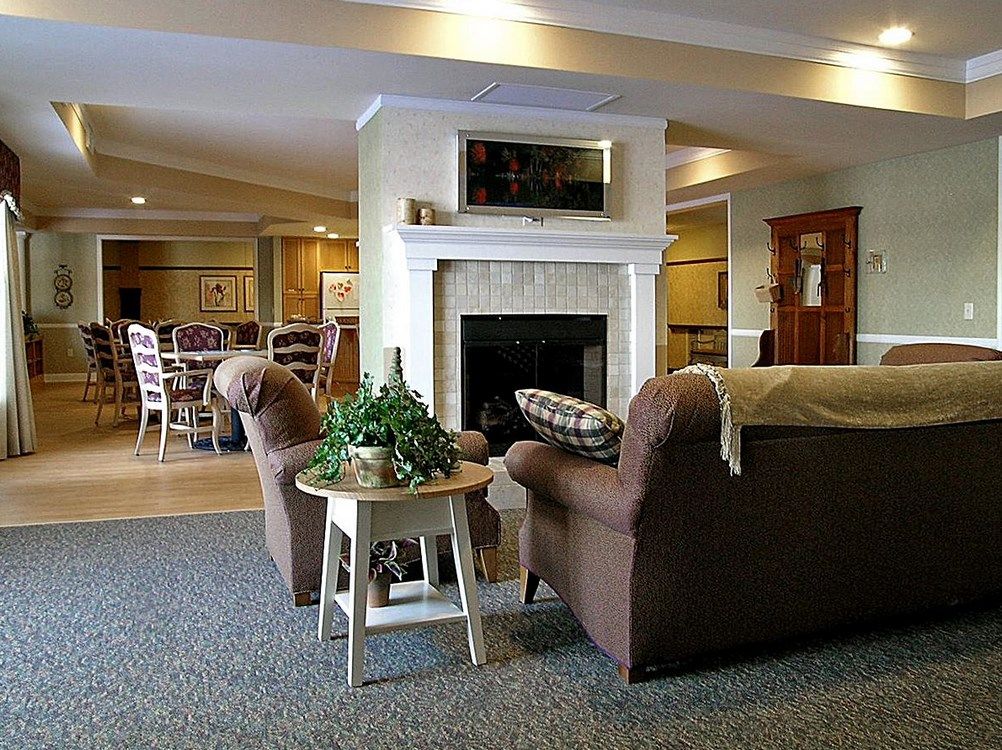A cozy living room with a fireplace, comfortable chairs, and a side table with plants.