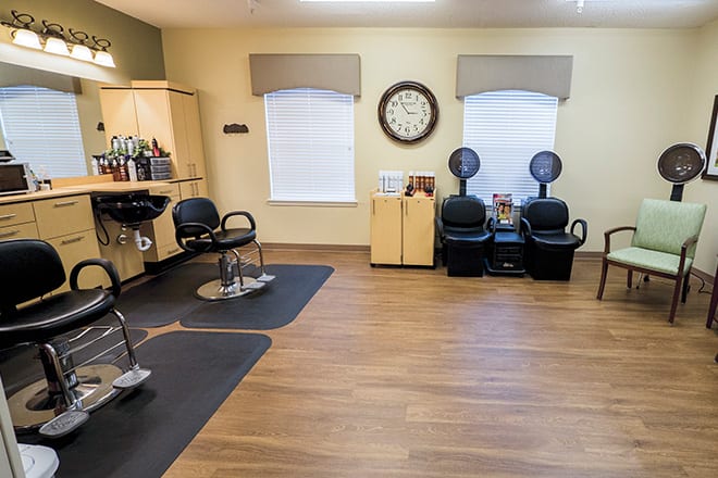 An interior view of a salon with chairs, hair dryers, and a wall clock.