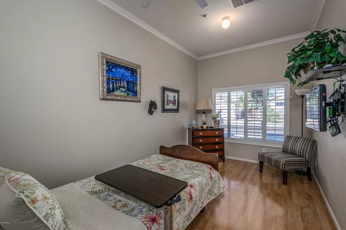 A cozy bedroom featuring a single bed, a dresser, and a window with shutters.
