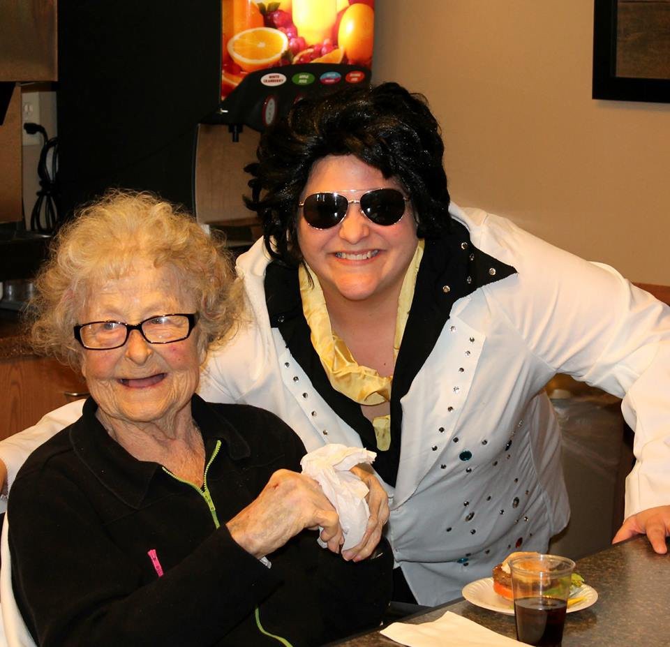 An elderly woman smiling at the camera with a person in costume standing next to her.