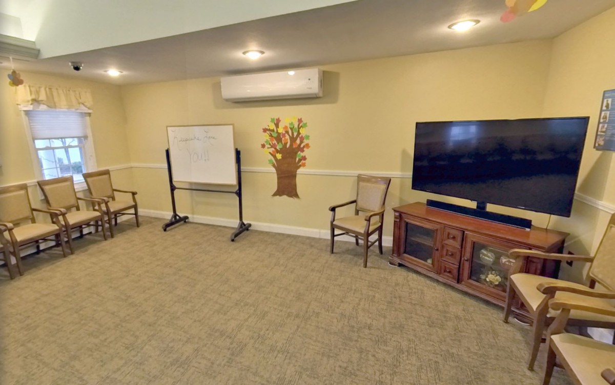 A cozy meeting room featuring a television, whiteboard, and seating area.