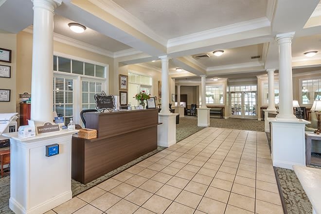 A spacious lobby area with a reception desk, tiled floors, and elegant columns.