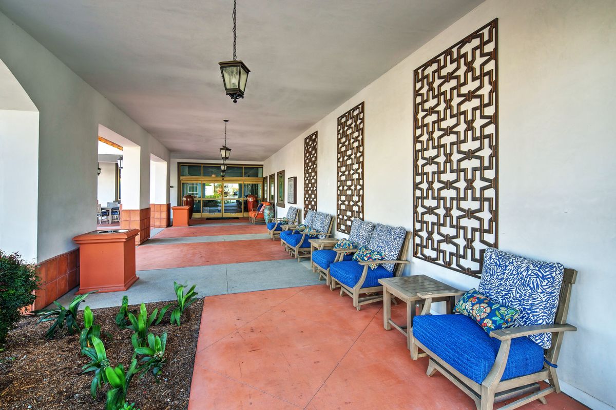 An inviting entrance corridor with blue-cushioned chairs and decorative panels along the walls.