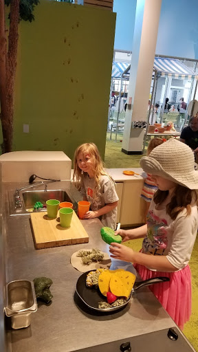 Kids engaged in a fun kitchen activity, exploring their creativity with colorful cups and pretend food.
