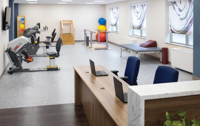 A spacious rehabilitation center with exercise equipment and a workstation.