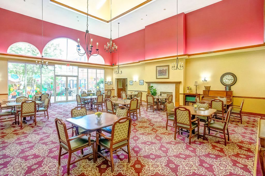 A spacious dining area with elegant tables and chairs, featuring a high ceiling and decorative lighting.