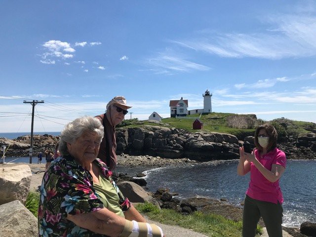 A group of people enjoying a sunny day near a lighthouse by the ocean.