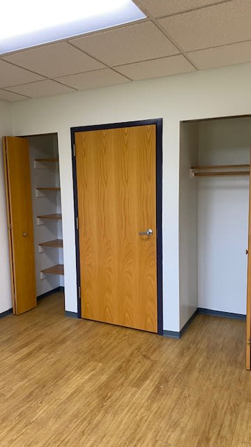 An empty room with open closets and wooden doors.