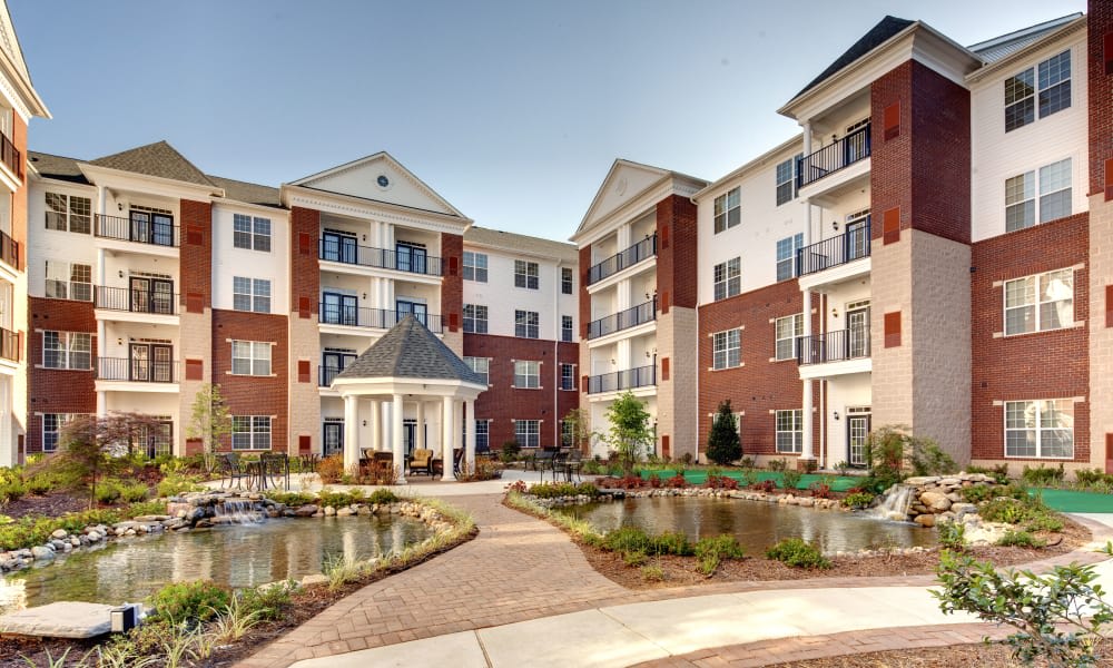 A modern residential apartment building with landscaped gardens and a small pond.