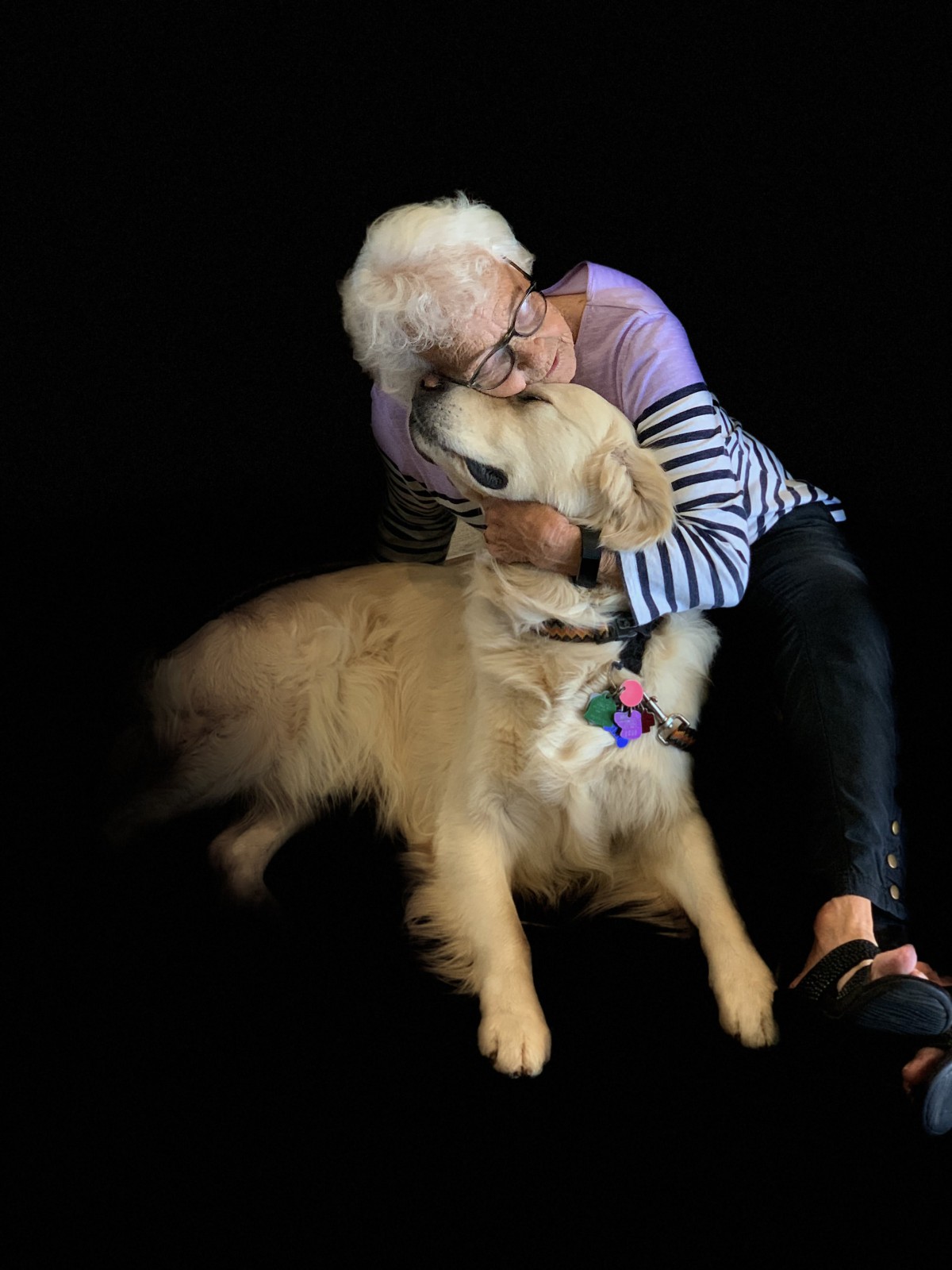 An elderly person joyfully hugs a golden retriever, showcasing companionship and affection.