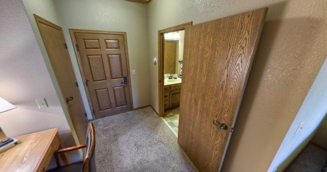 View of a bedroom leading to a bathroom with wooden doors.